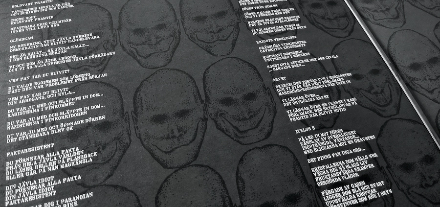 A closeup shot of the inside of the gatefold cover. The lyrics are printed in white on a black background filled with weird looking faces.