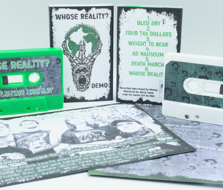A photo of two of the cassette versions being laid out in detail. The tape to the left is neon green while the tape on the right is white. In front of them there's the unfolded j-cards.